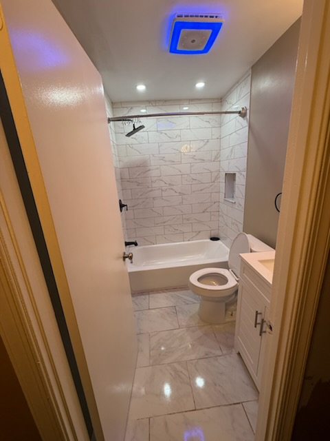 Compact bathroom with subway-tile tub surround, marble floor and modern vanity