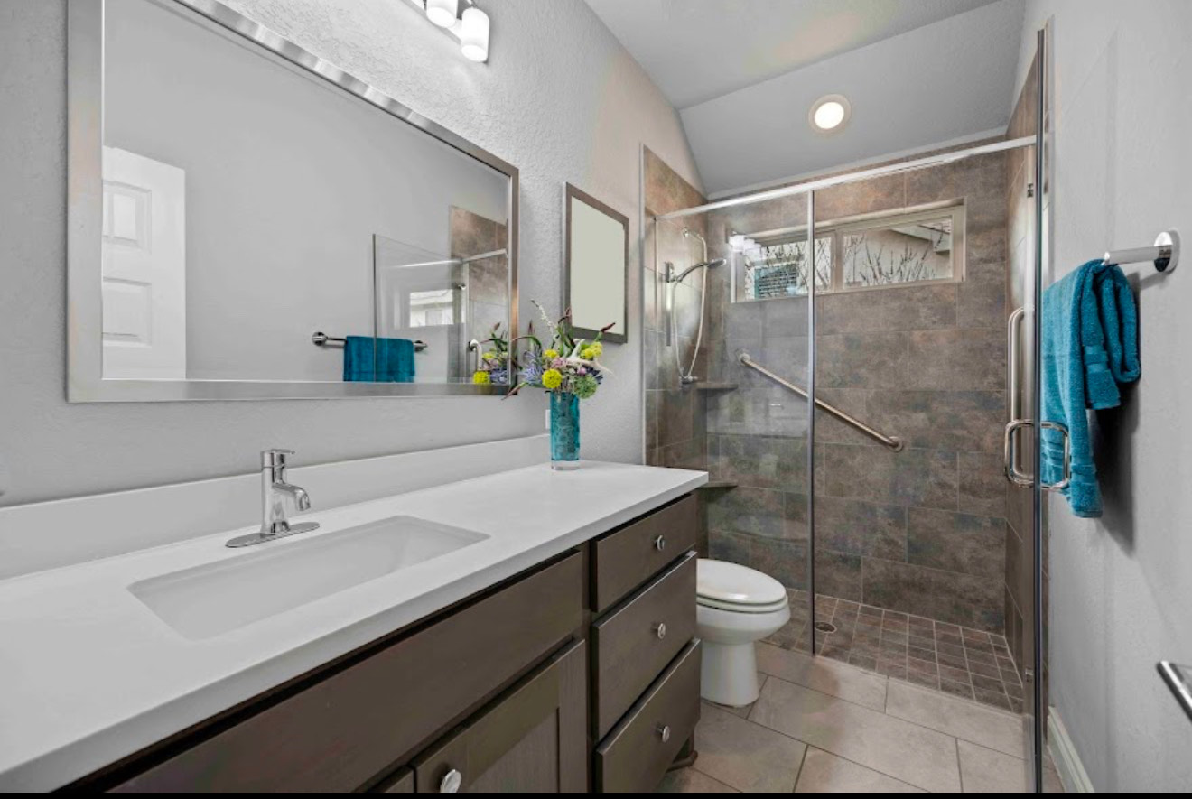 Full bathroom with floating vanity, wide mirror and frameless tile shower with bench
