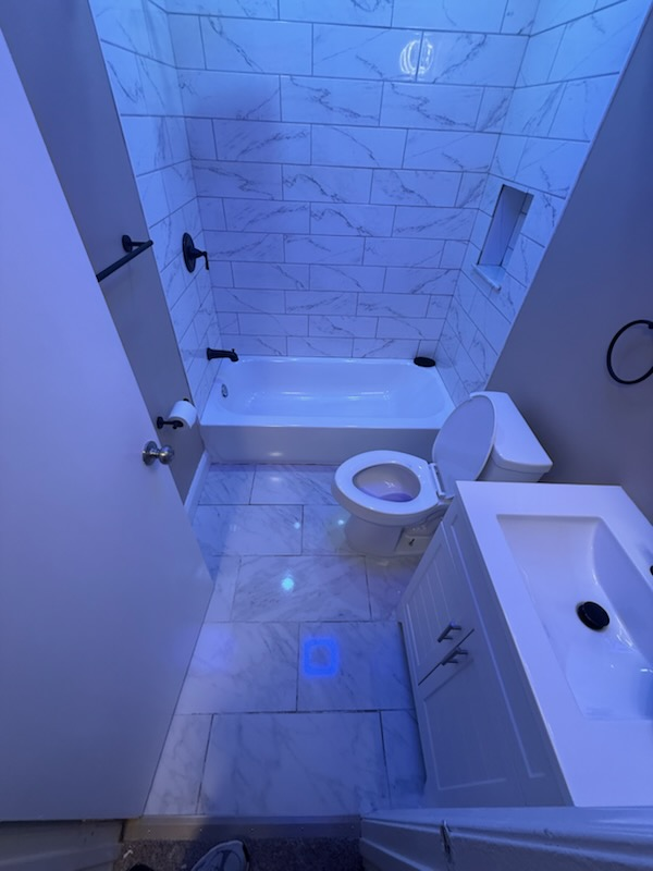 Modern tiled tub-and-shower combination with marble surround and matte black trim