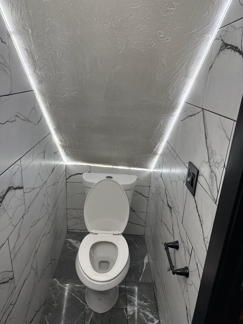Marble water closet with concealed LED cove lighting and matte black fixtures